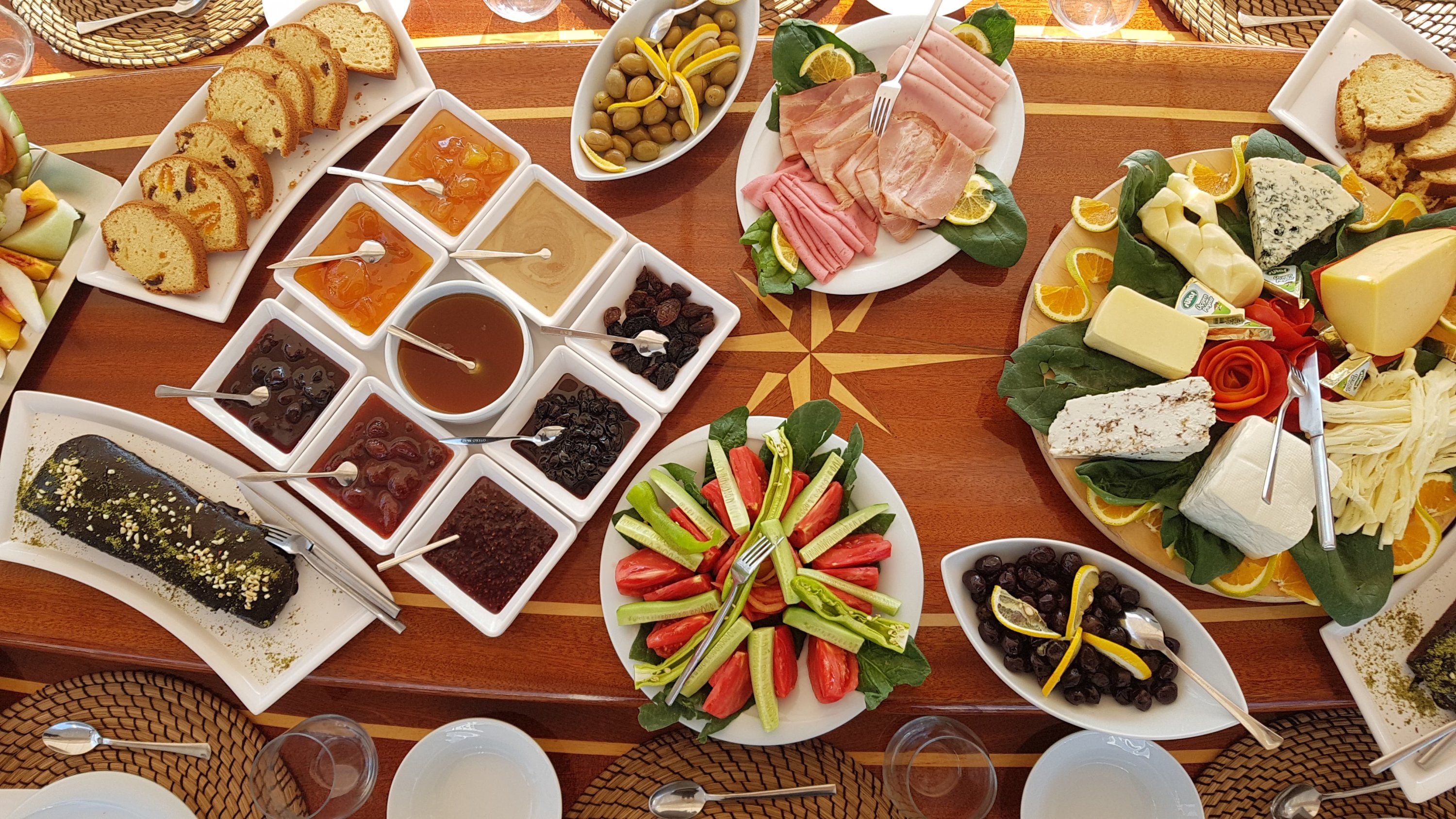 A wide variety of food in white serving plates on a wooden table 