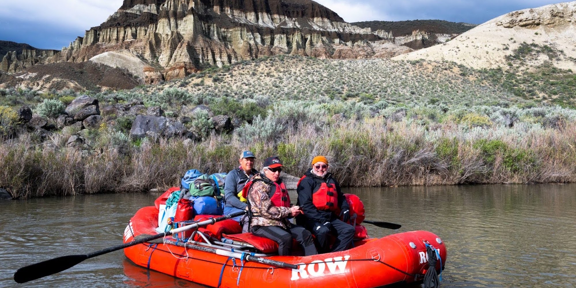 Whitewater rafters posing for a photo on the Owyhee River in front of unique canyon geology