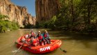 Two guests and a raft guide all smiling while on the Bruneau River on a sunny day