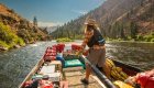 Man driving the legendary sweep boat down the Middle Fork Salmon River on a sunny day