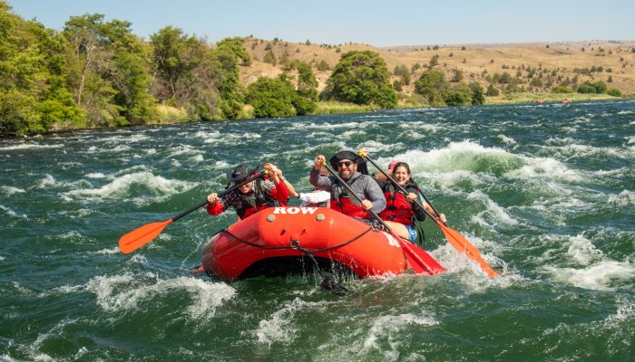 Group of paddlers in a red raft going through a rapid on the Deschutes River